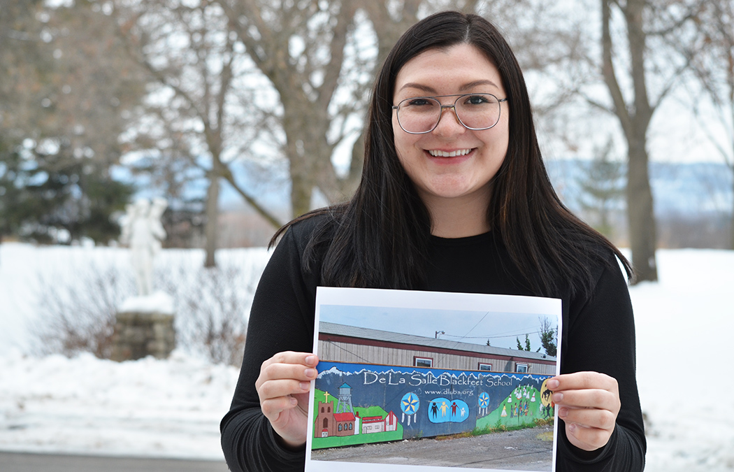 Aimee Boggs holding photo of De La Salle Blackfeet School