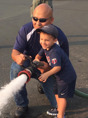 George Diaz shows his son, Sam, how to use the fire hose. Says Diaz: “When we're out in the community, the kids will remember that we were at their schools and come talk to us.”