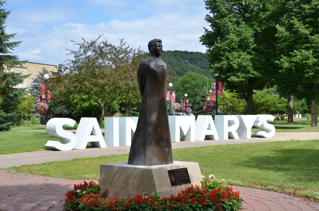 Statue in front of large, out door letters spelling "Saint Mary's" at Winona Campus