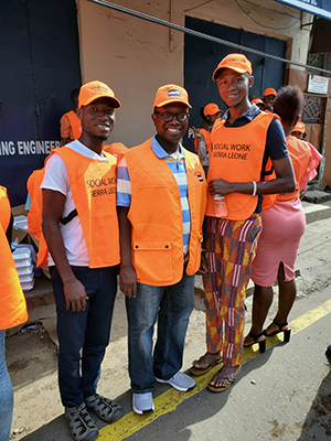 Sylvester Amara Lamin poses with two workers from Social Workers Sierra Leone. Lamin spent a Sunday handing out food to the homeless and mentally ill who live on the streets of Freetown, Sierra Leone, on a recent trip back to his native country.