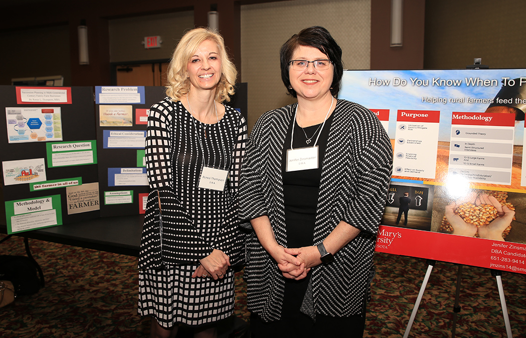 Portrait photo of Renee Thompson and Jenifer Zinsmaster, standing next to their posters at the 16th annual Doctoral Research Symposium on March 7 on the Twin Cities Campus.