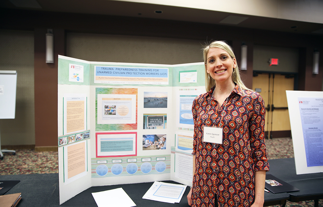 This is a photo of Karen Spencer in front of her poster at the 16th annual doctoral research symposium on the Twin Cities Campus.