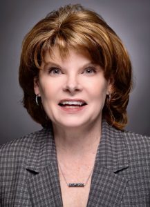 Headshot of smiling woman wearing a checkered blazer.